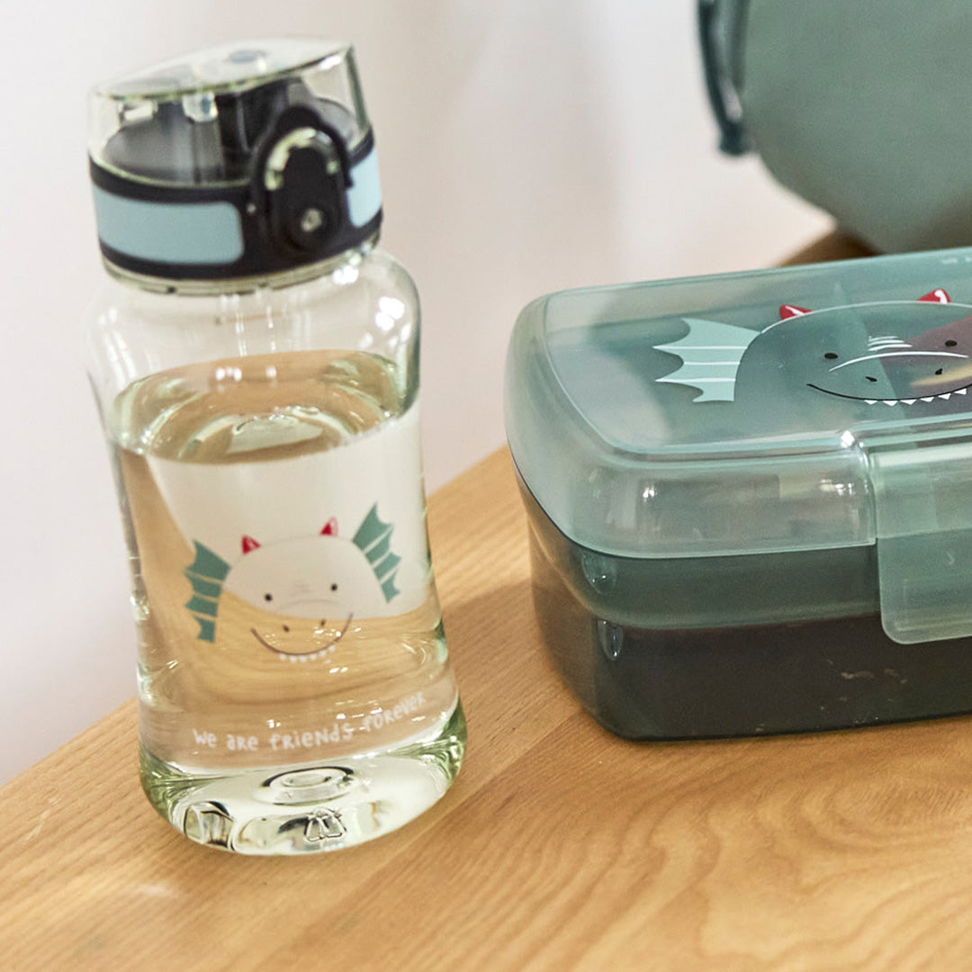 Lässig kinderdrinkfles met draak, gevuld met water, naast een bijpassende lunchbox op een houten plank.
