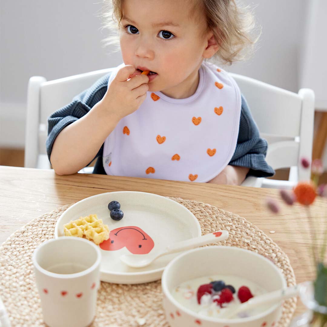 Peuter eet aan tafel met lässig kinderservies met hartjes.