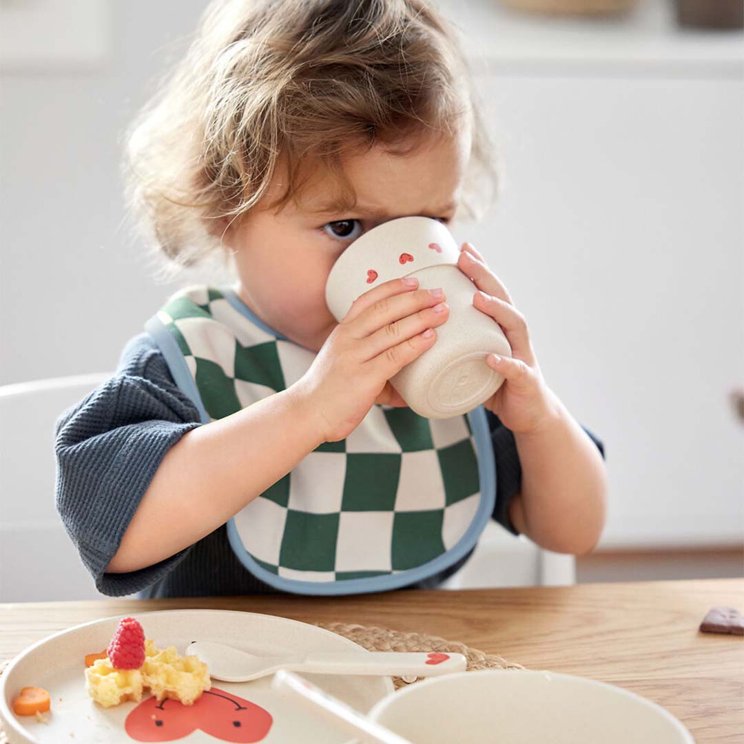Peuter drinkt uit de lässig kindermok met rode hartjes.
