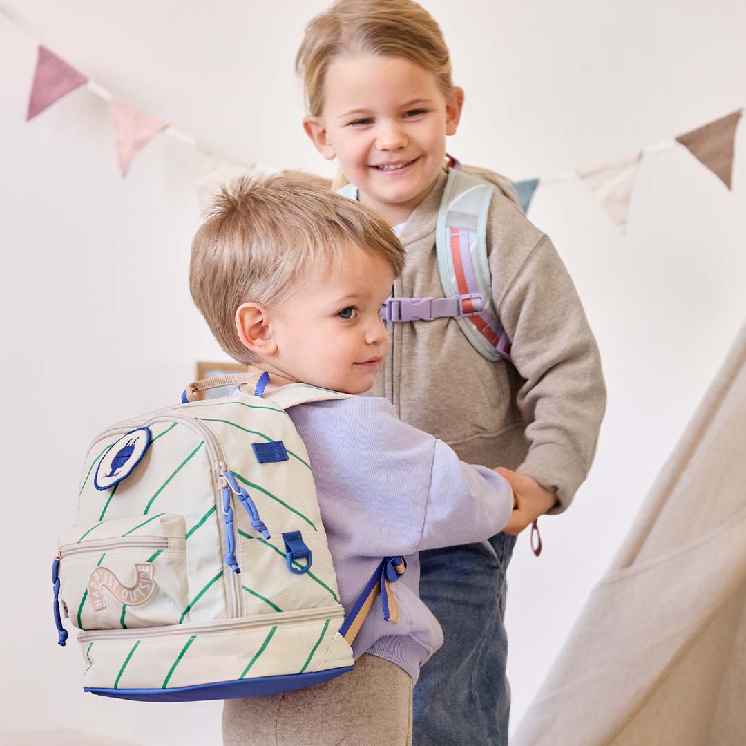 Twee lachende kinderen met rugzakken, de jongen draagt de Lässig kleuterrugzak met kikker.