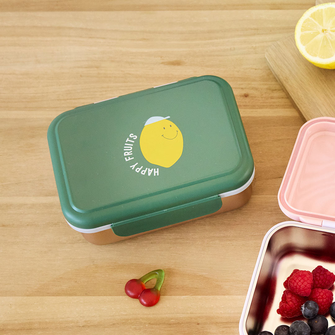 Lässig kinderbroodtrommel met groene deksel en citroenprint, staand op een houten tafel met fruit en snoep.