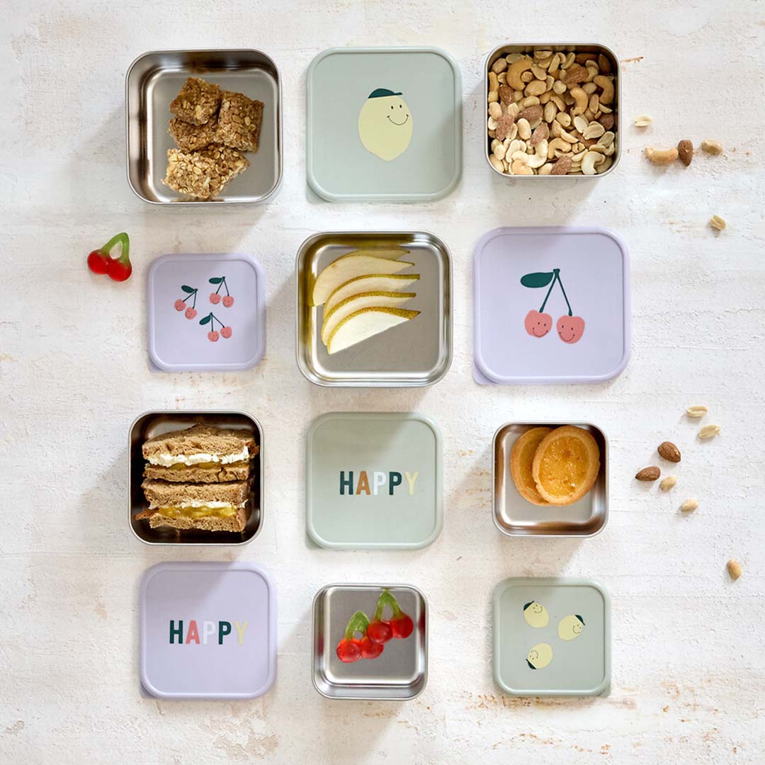 Overzicht van Lässig rvs snackdoosjes voor kinderen, gevuld met diverse snacks, met deksels met kersen, citroenen en 'HAPPY' opdruk.