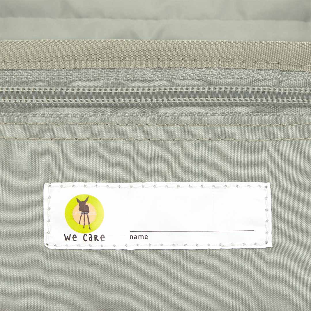 Detail van het 'We Care' naamlabel in de Lässig toilettas.