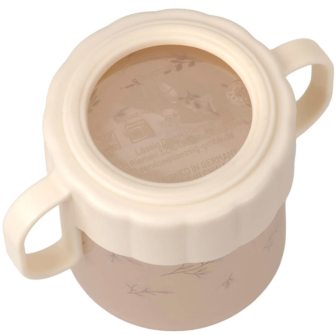 Bovenaanzicht van de Lässig tuitbeker met bladerenpatroon, met zicht op de binnenkant van de beige deksel.