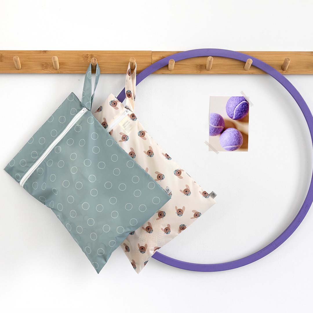 Twee lässig waterproof opbergzakken, één met stippen en één met hondenprint, hangend aan een houten rek.