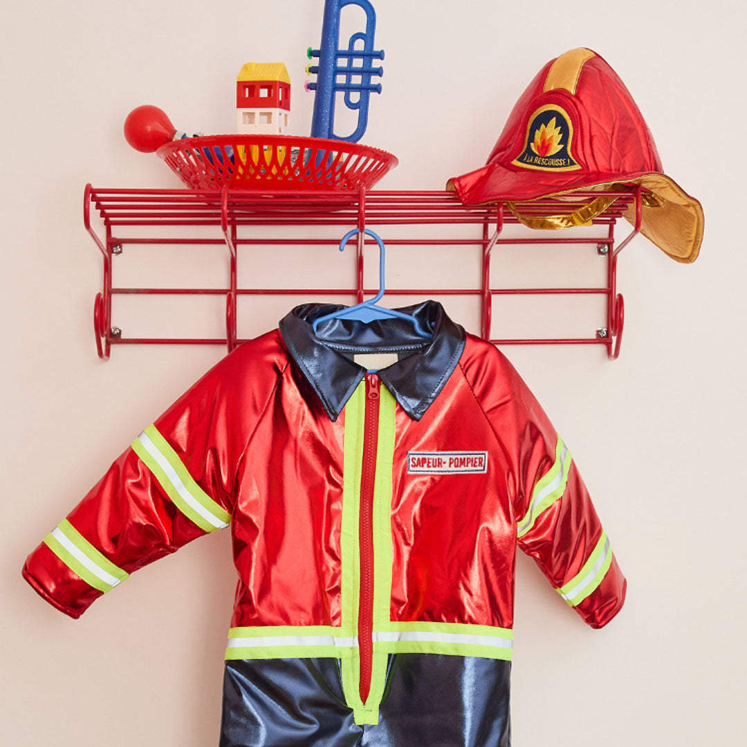 le petit souk brandweerhelm op een plank boven een rood brandweerpak dat aan een rek hangt.