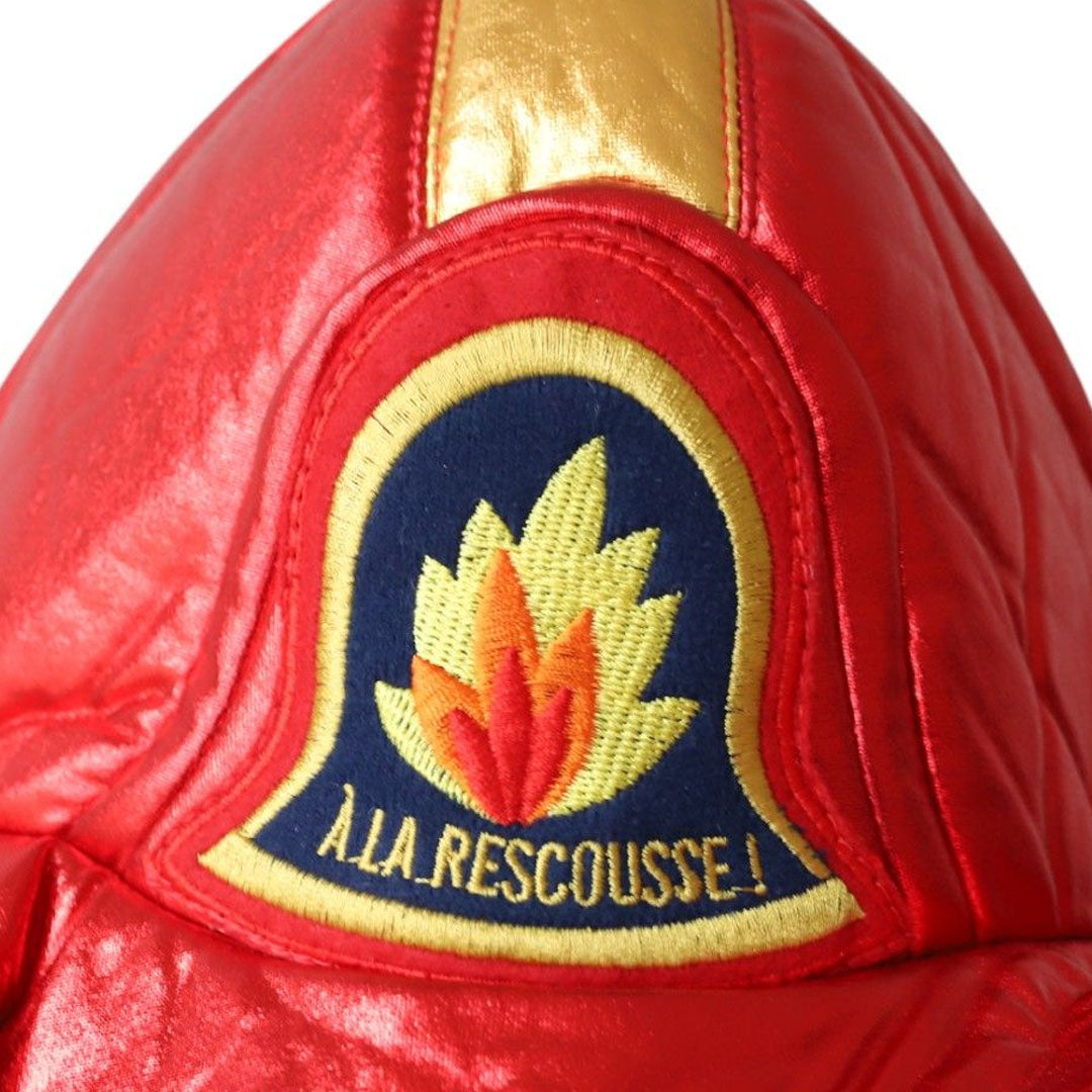 Detail van het embleem op de le petit souk brandweerhelm, met vlammen en de tekst 'À LA RESCOUSSE!'.