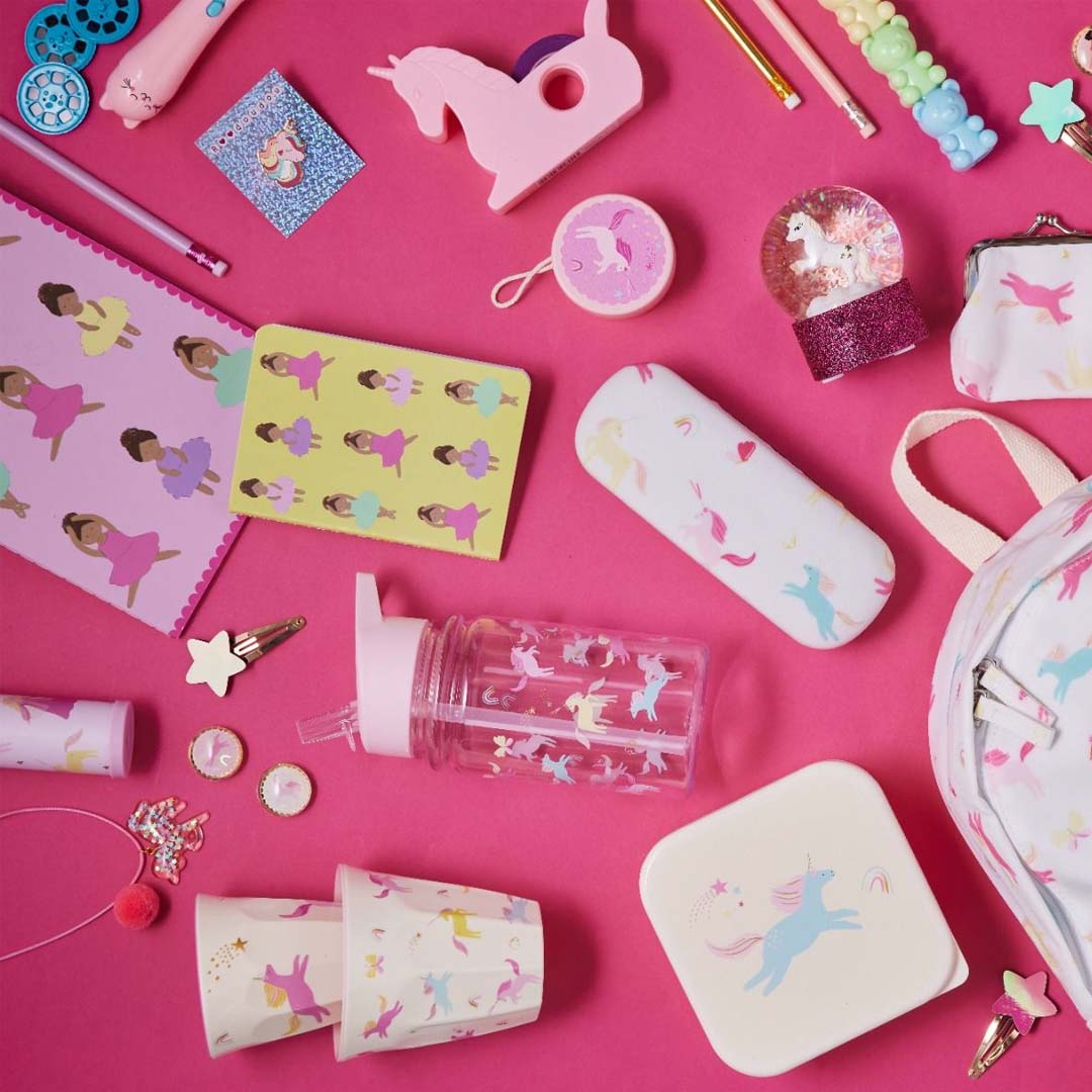 Overzicht van diverse le petit souk eenhoorn-thema speelgoed en accessoires, waaronder een drinkfles, op een roze achtergrond.