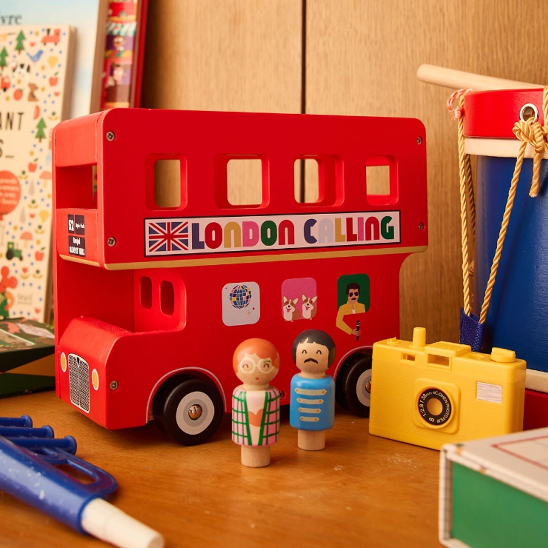 le petit souk houten dubbeldekker speelbus met twee houten poppetjes ernaast, op een houten ondergrond.