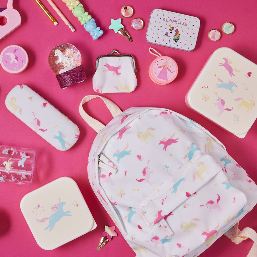 Een collectie le petit souk kinderaccessoires met eenhoornpatroon, waaronder een rugzak en etui, op een roze achtergrond.