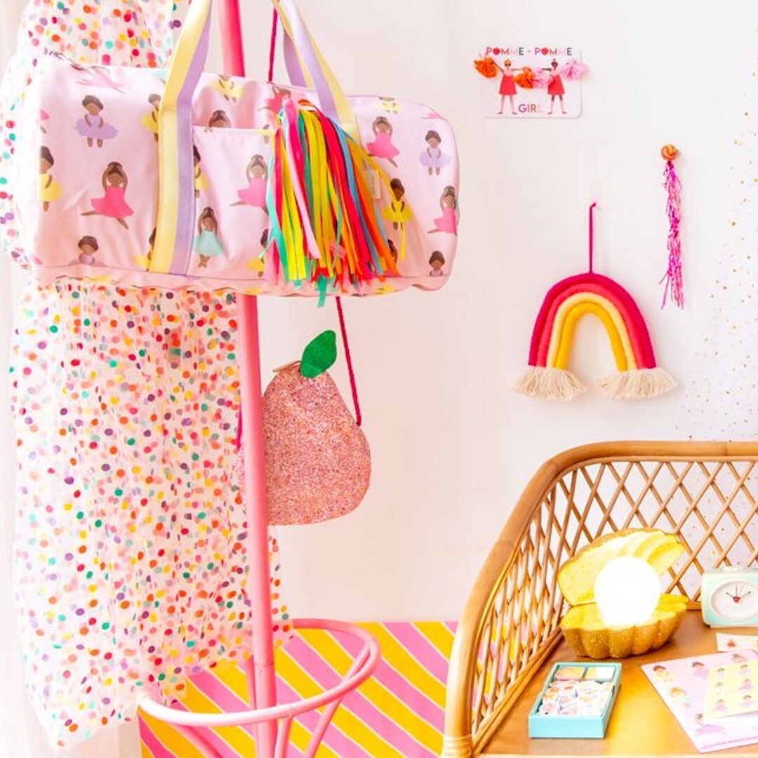Le Petit Souk roze glitter kindertas in de vorm van een peer hangend aan een standaard in een kleurrijke kinderkamer.