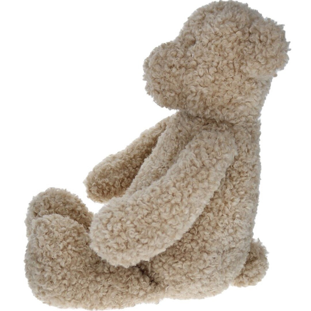 le petit souk knuffelbeer van beige pluche met textuur, zittend en schuin van achteren gezien.