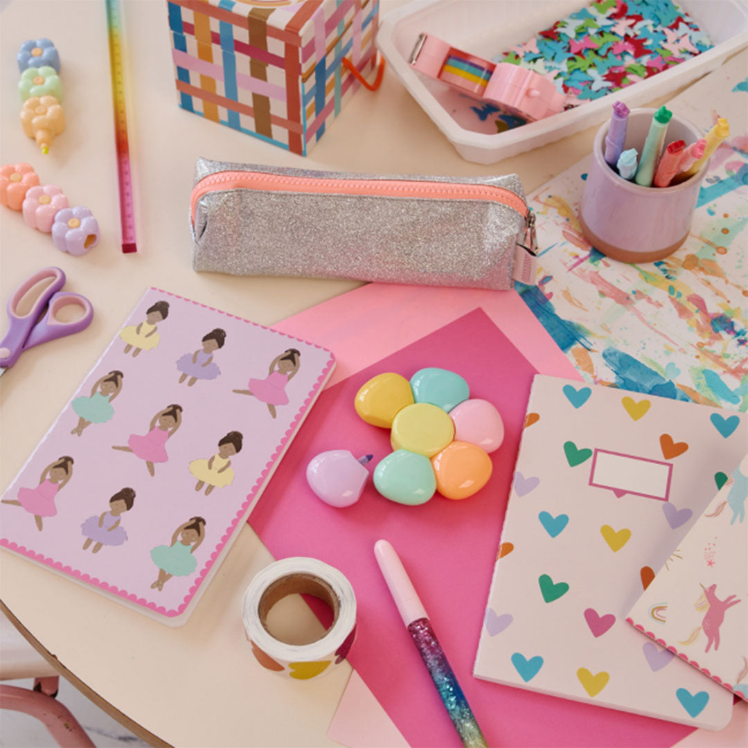 Een bureau vol schoolspullen met de le petit souk bloem markeerstift set en andere creatieve benodigdheden.