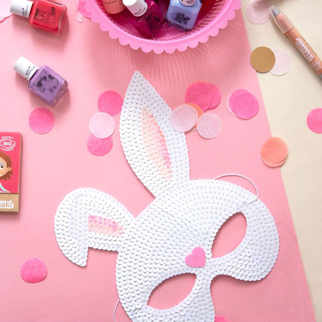 Le petit souk wit konijnenmasker met pailletten op een roze ondergrond met confetti en nagellak.