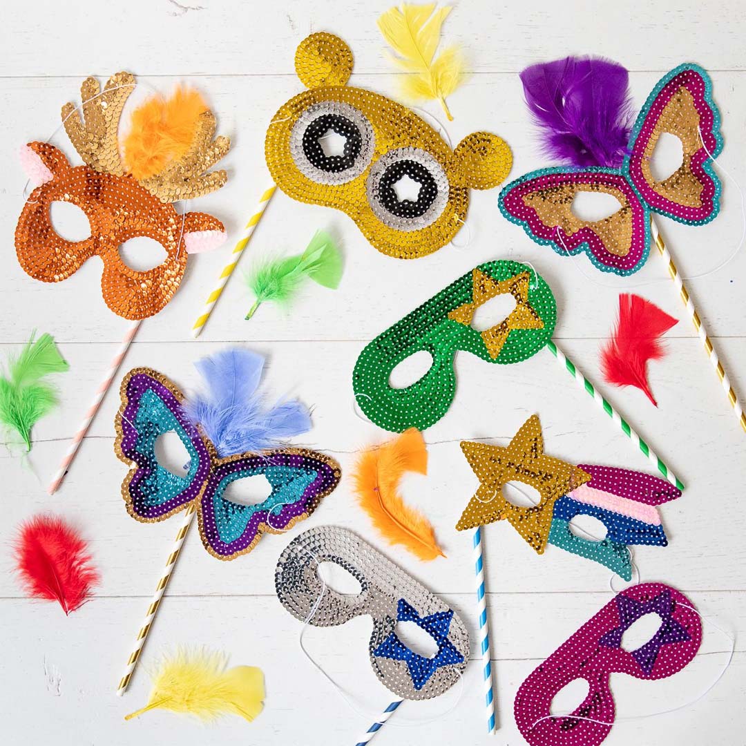Diverse Le Petit Souk maskers met pailletten in verschillende dier- en stervormen, liggend op een witte ondergrond.