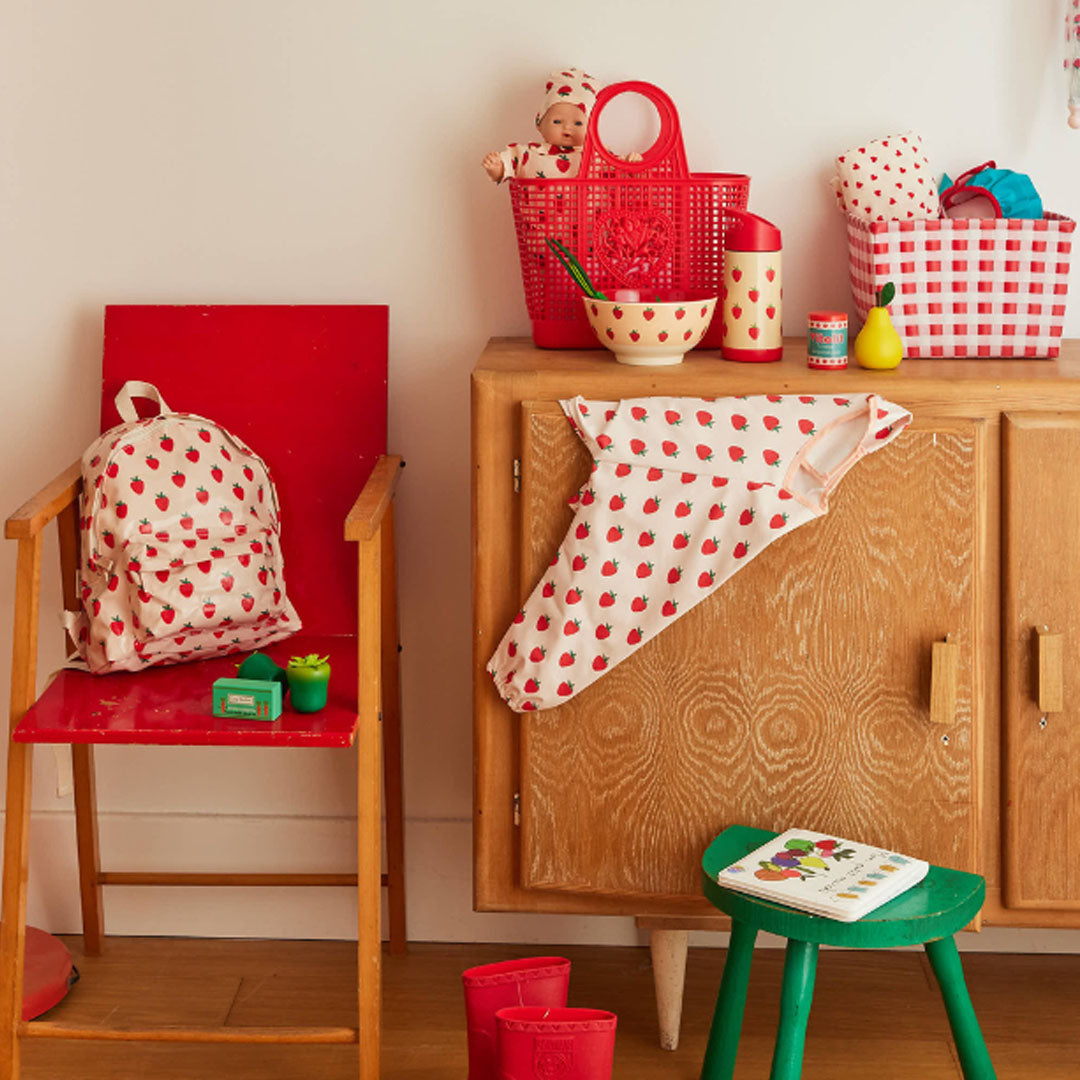 le petit souk mouwslab met aardbeipatroon, gedrapeerd over een kast in een kinderkamer.