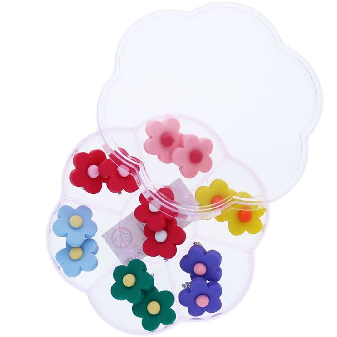 le petit souk set van 7 paar bloemvormige clip-on oorbellen in een open plastic doos.