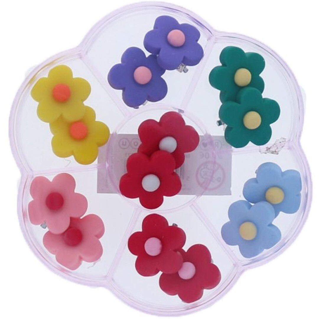 le petit souk set van 7 paar bloemvormige clip-on oorbellen in een gesloten plastic doos, van bovenaf gezien.