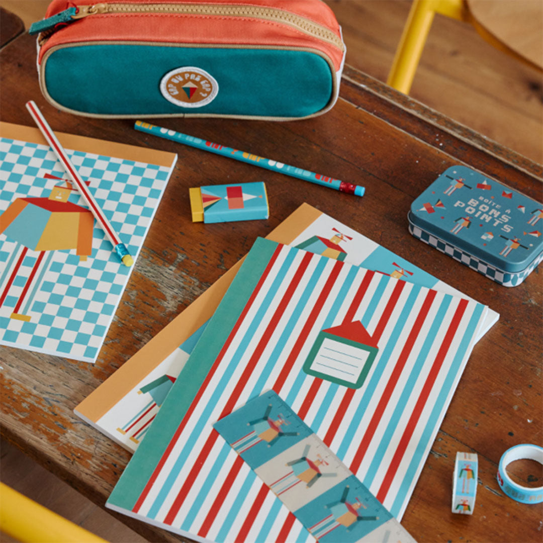 Le petit souk schrift met rood-blauwe strepen en andere bijpassende kantoorartikelen op een houten bureau.
