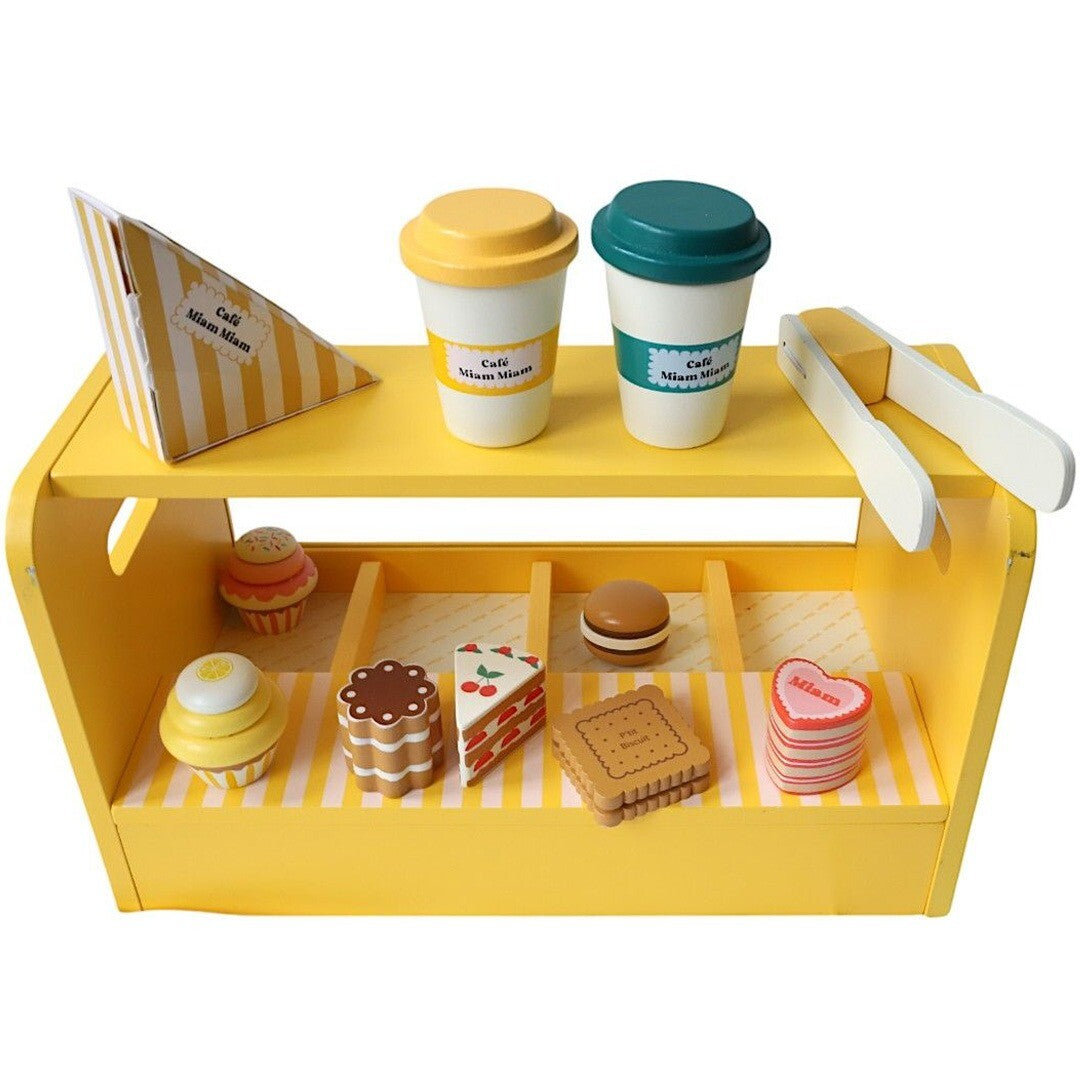 Le petit souk houten keukenspeelset met gele toonbank, twee koffiekopjes, tang en diverse speelgoedgebakjes en koekjes.