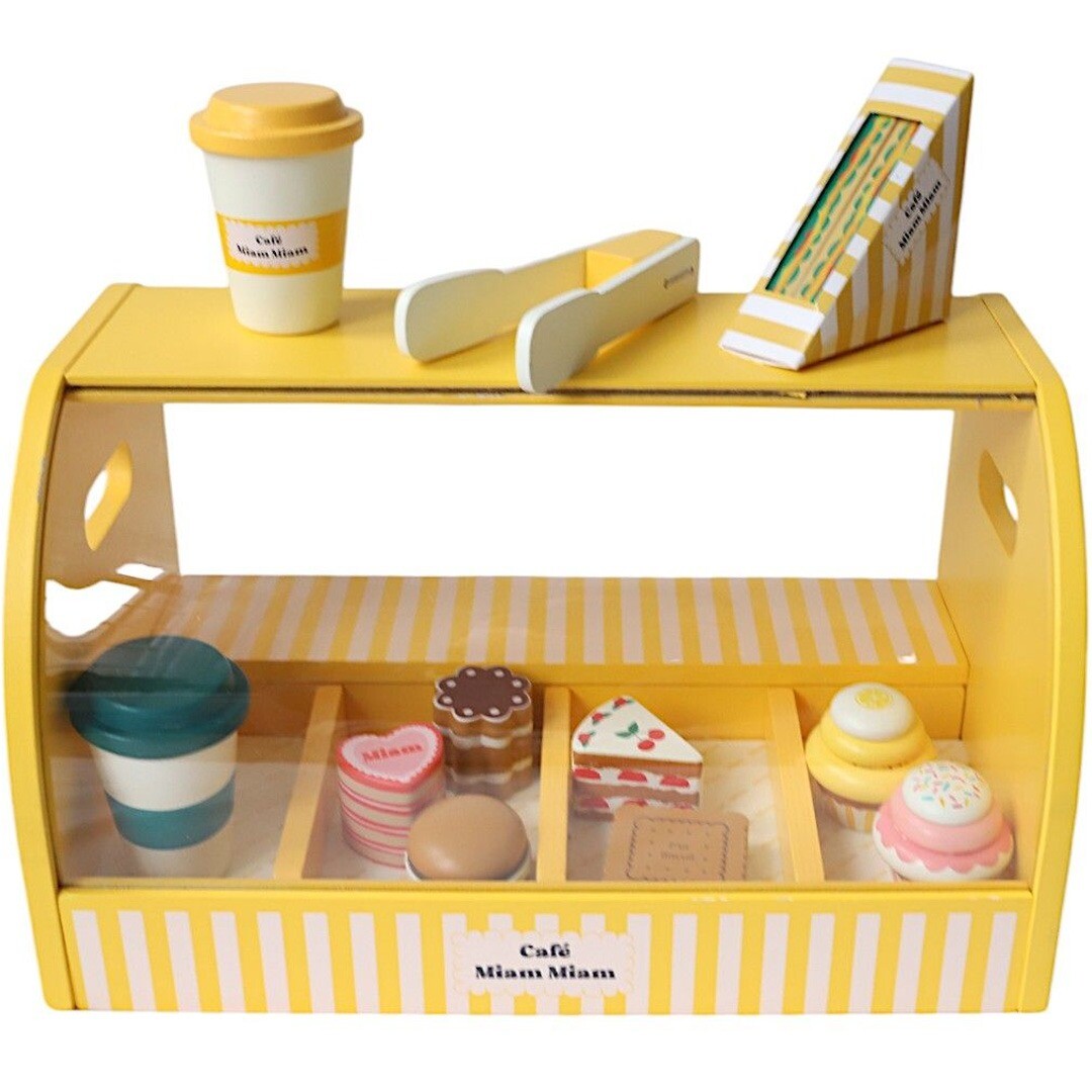 Le petit souk houten keukenspeelset met gele toonbank, gevuld met speelgoedgebakjes en een koffiekopje, met een koffiekopje, tang en sandwich op de bovenkant.