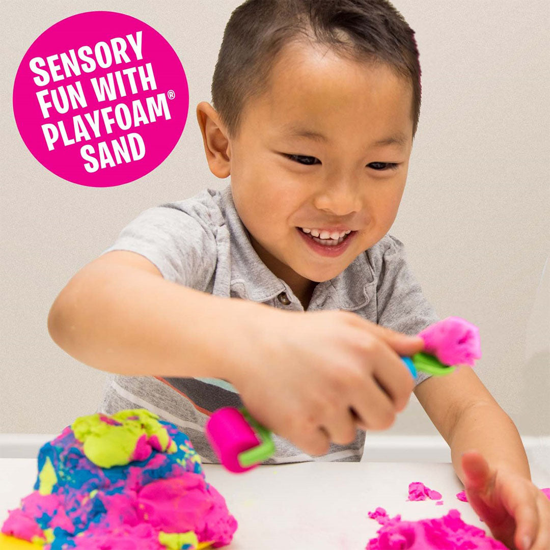 Een lachende jongen speelt met Playfoam Sand en een roller.