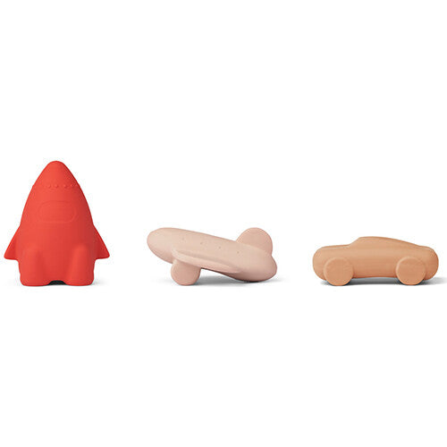 Drie Liewood rubberen badspeeltjes voor baby's in de vorm van een rode raket, een roze vliegtuig en een beige auto, op een rij.
