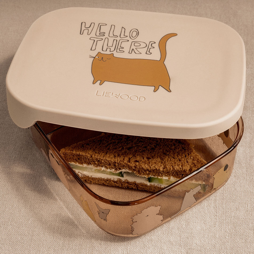 Open Liewood broodtrommel met een sandwich erin, de beige deksel is opengeklapt en de transparante onderkant heeft katten en honden.