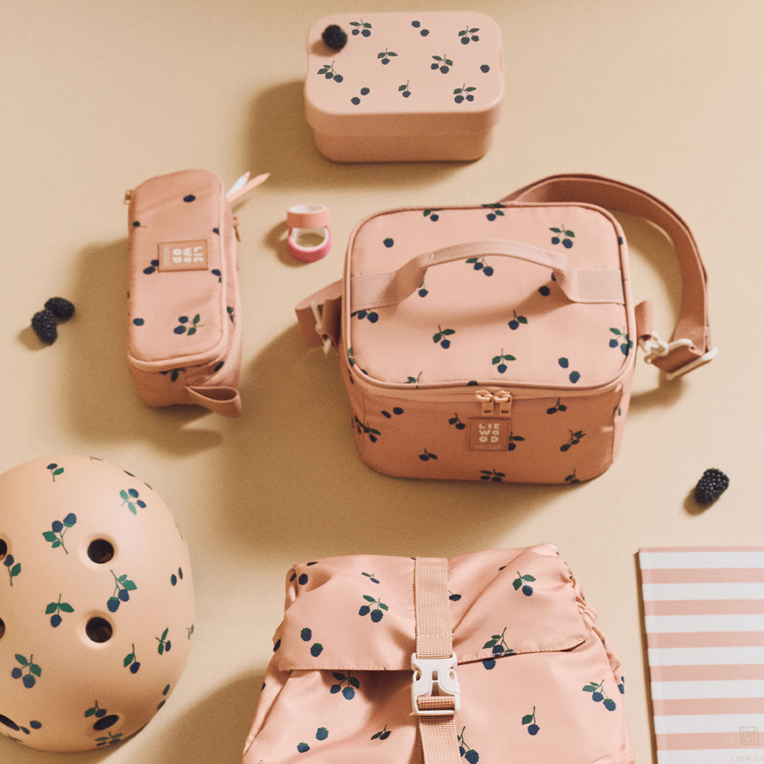 Collectie Liewood roze schoolspullen met bessenpatroon, waaronder een lunchbox, etui, tas, helm en rugzak.