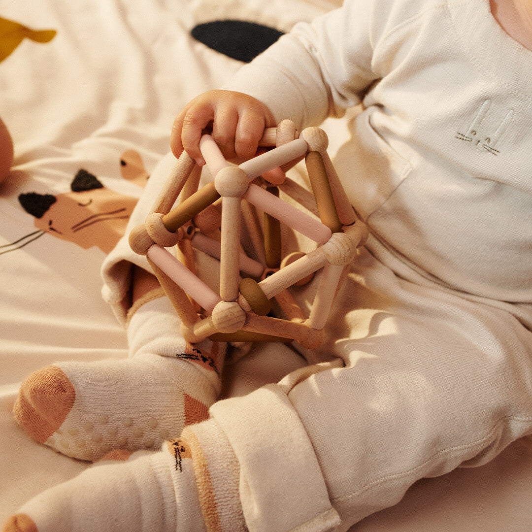 Een baby houdt het Liewood grijpspeeltje Annemette vast met beide handen.