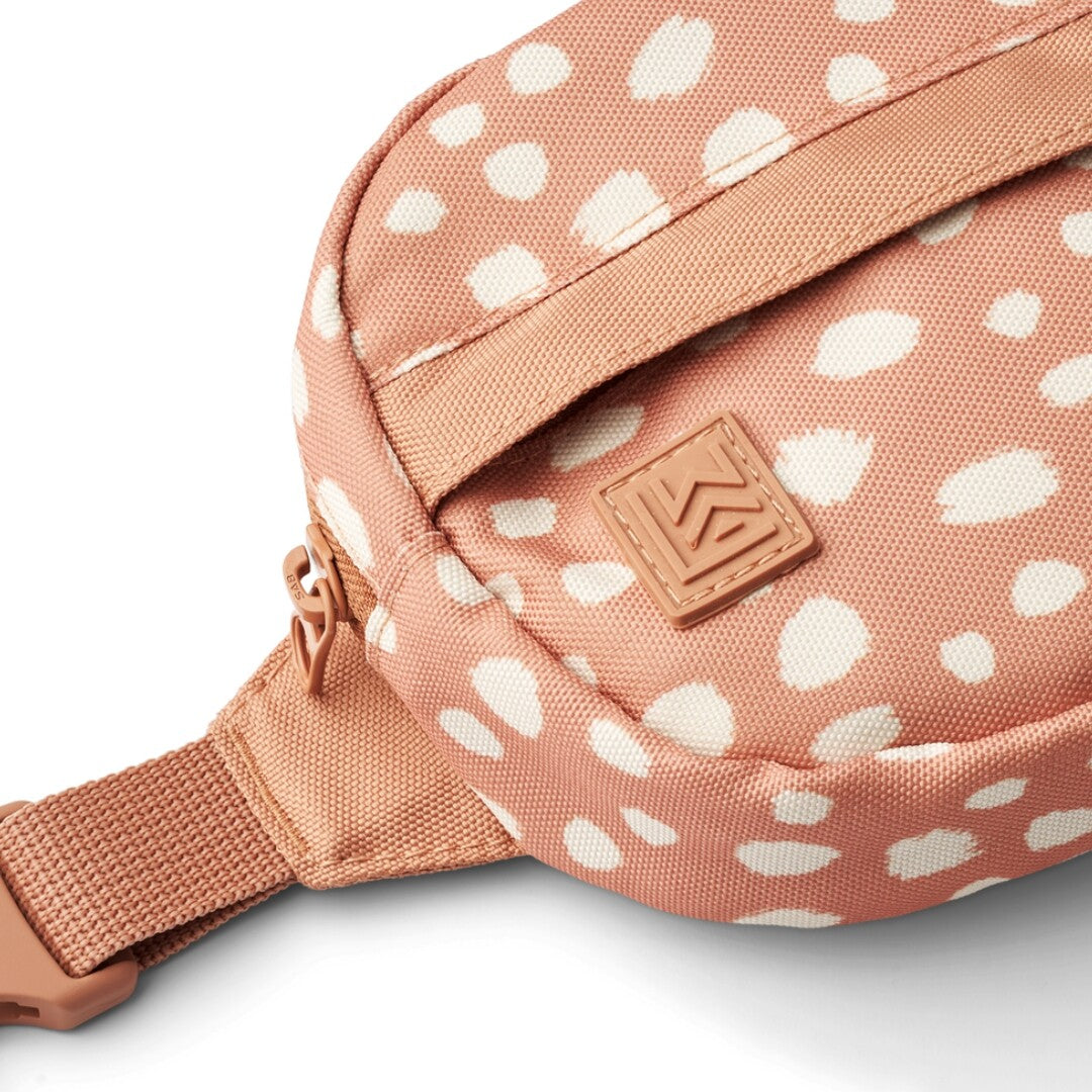 Detailopname van de Liewood kinderheuptas met roze stof, witte stippen en het merklogo.