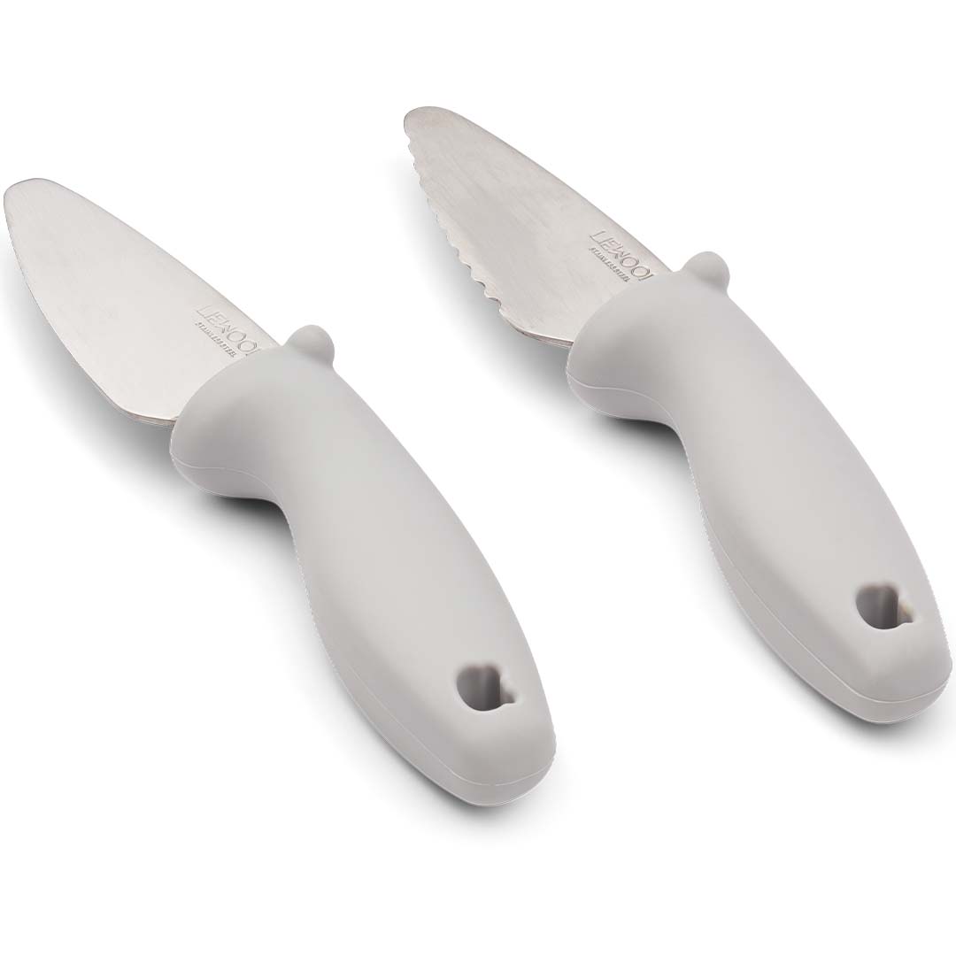 Twee Liewood kindermessen met lichtbeige siliconen handvatten, één met een gekarteld en één met een glad roestvrijstalen lemmet, schuin van bovenaf gezien.