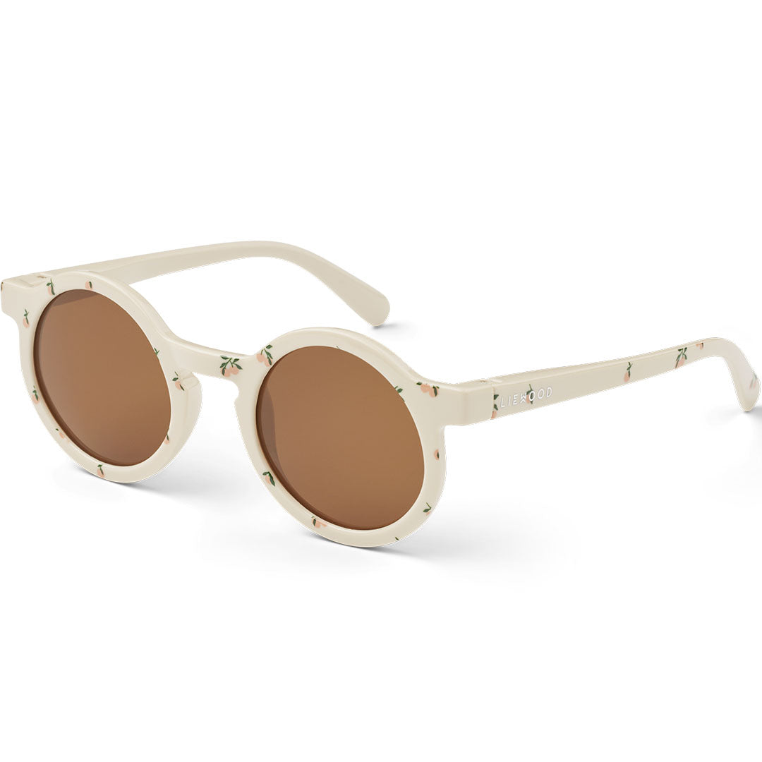 Liewood kinderzonnebril Darla in beige met perzikjespatroon, schuin gefotografeerd.