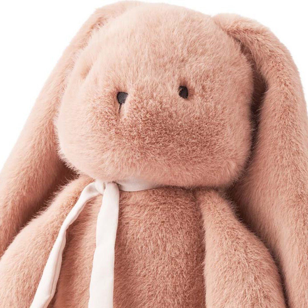Close-up van de kop en het bovenlichaam van een roze pluchen knuffelkonijn met een wit lint.