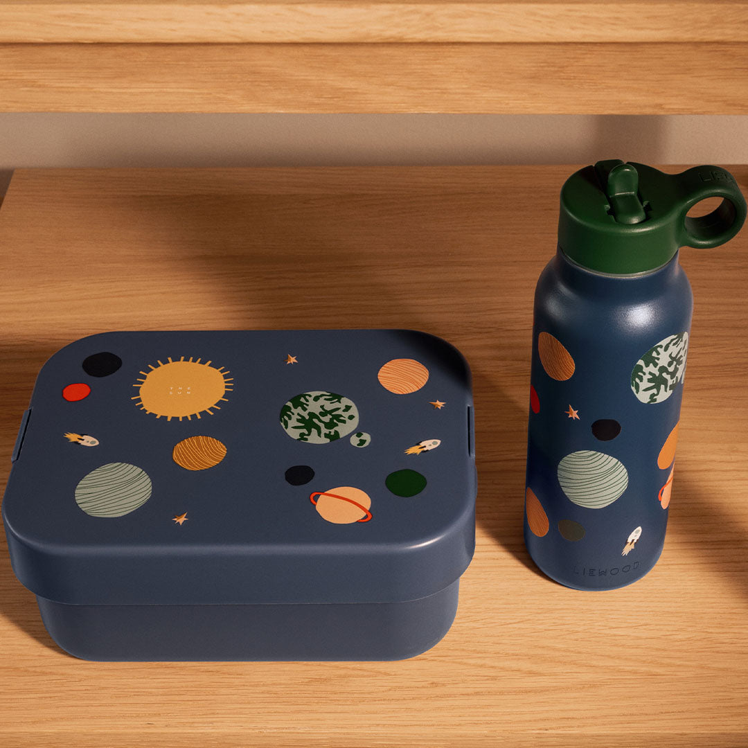 Liewood kinder lunchset met blauwe broodtrommel en drinkfles met universumthema op een houten ondergrond.