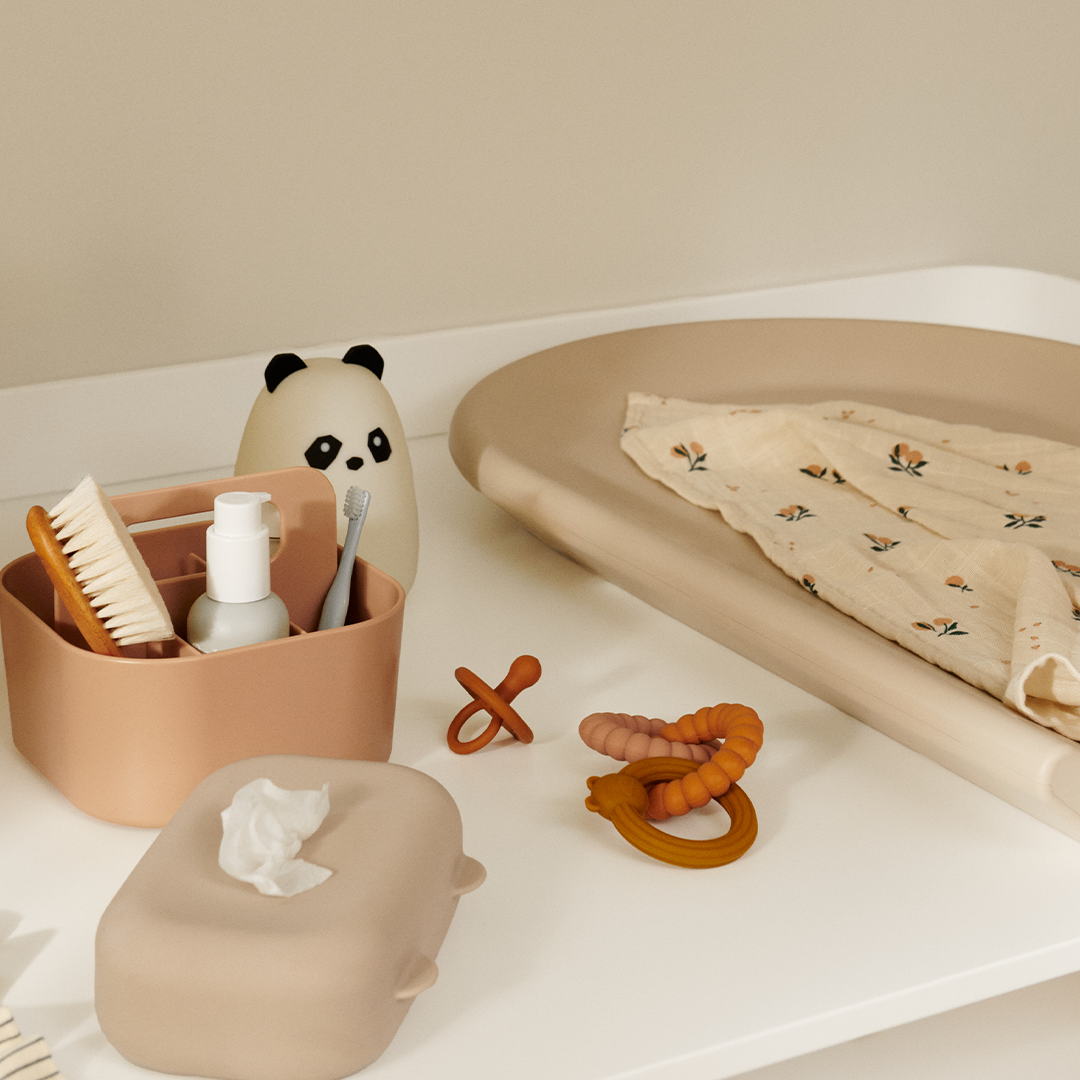 Het Liewood panda nachtlampje staat op een commode tussen andere babyverzorgingsproducten.