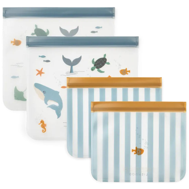 Vier Liewood herbruikbare voedselzakjes, twee met zeedieren en twee met blauw-witte strepen.