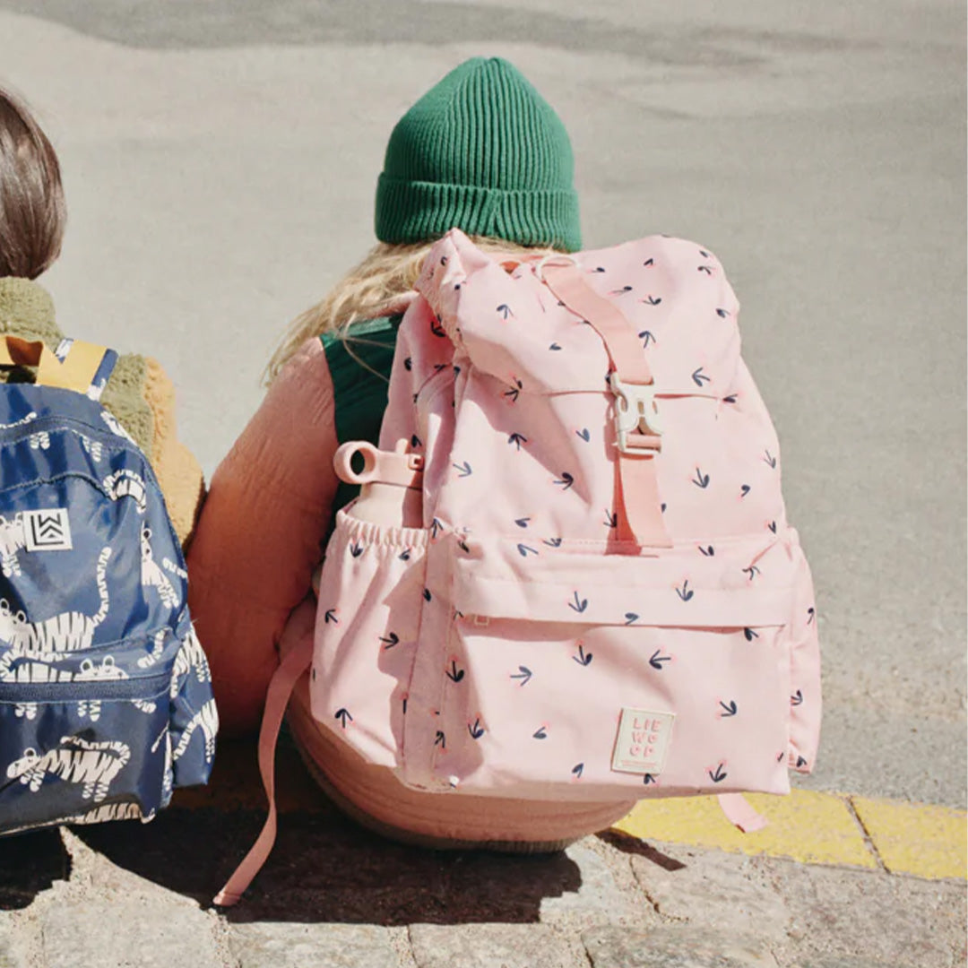 Kind draagt de roze Liewood kinderrugtas Johnny met cherry heart patroon, met een drinkfles in het zijvak.