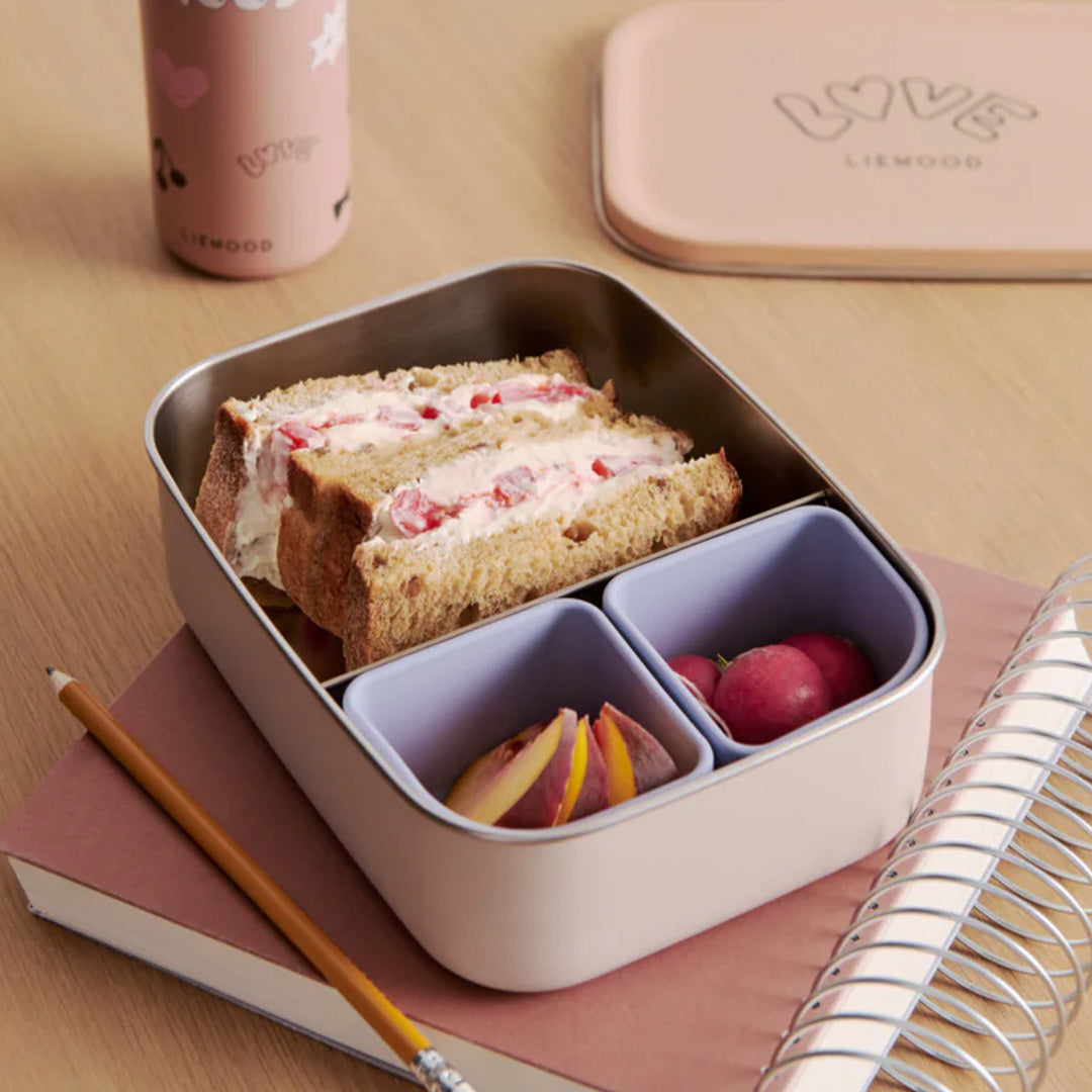 Liewood RVS broodtrommel Nina gevuld met een sandwich en fruit, met de deksel ernaast.