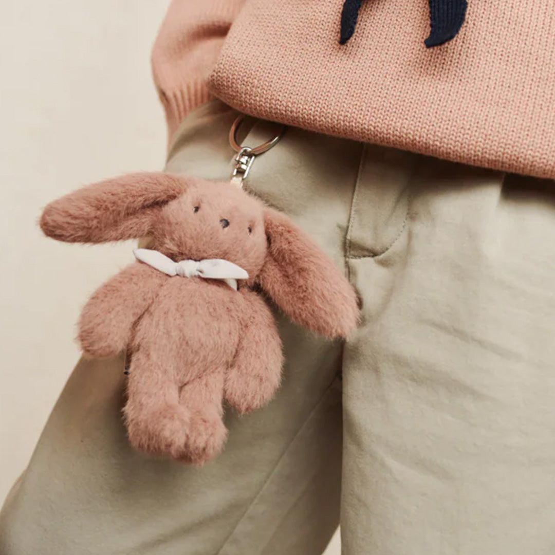 Liewood pluche roze konijn sleutelhanger hangend aan de riemlus van een beige broek.
