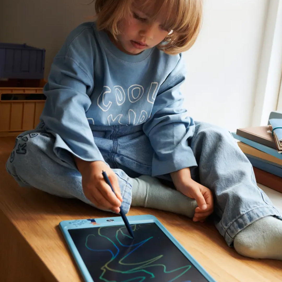 Een kind tekent met een stylus kleurrijke krabbels op een blauw tekentablet.