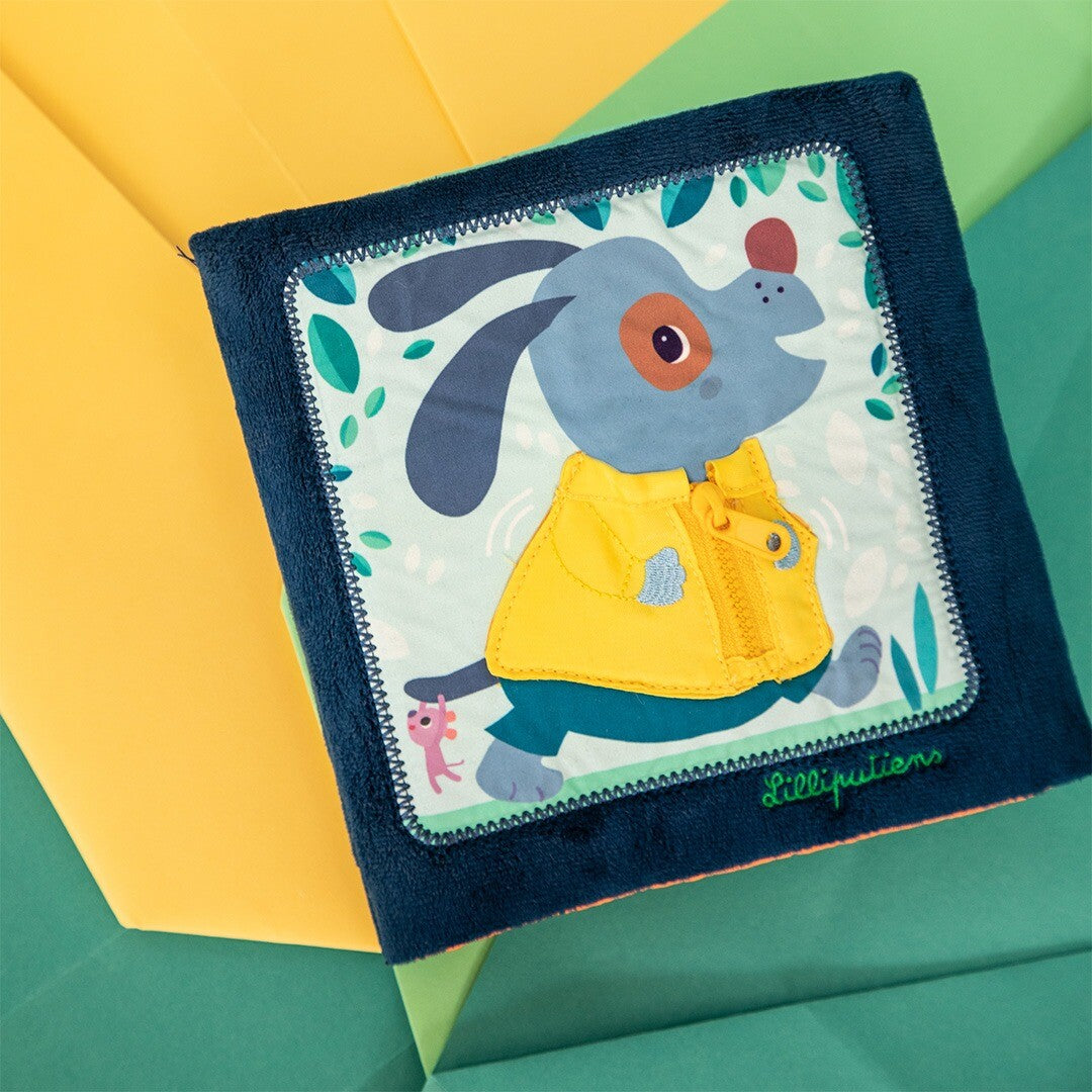 Lilliputiens babyspeelgoed activiteitenboek met de blauwe hond Jules met geel jasje, schuin gefotografeerd.