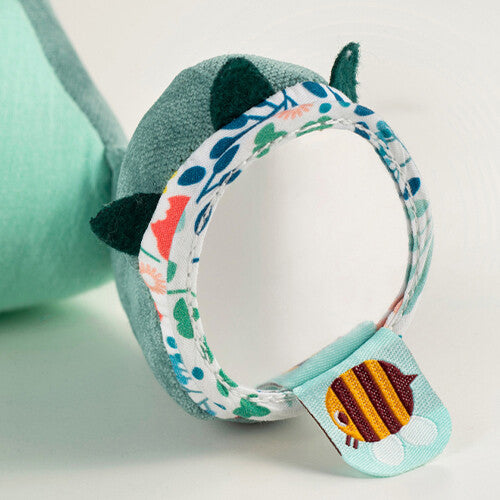 Detail van de Lilliputiens activiteitenknuffel Joe met een gebloemde stoffen ring en een label met een bij.