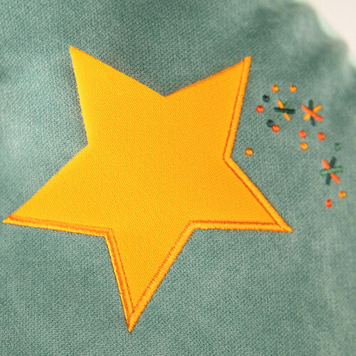 Close-up van een gele geborduurde ster met oranje stippen op de groene Lilliputiens activiteitenknuffel.