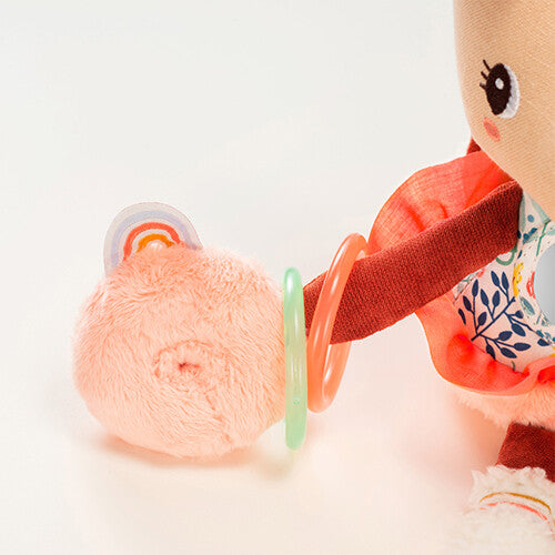 Detail van de linkerhand van Lilliputiens activiteitenknuffel Stella met roze rammelaars en een regenboogje.