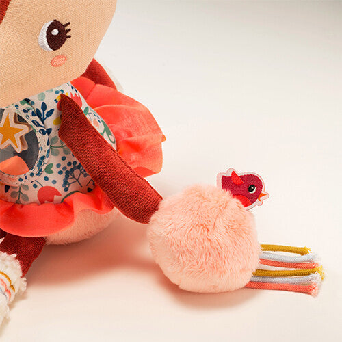 Detail van de rechterhand van Lilliputiens activiteitenknuffel Stella met roze rammelaars en een rood vogeltje.