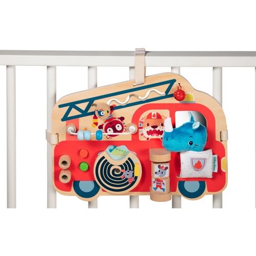 Het lilliputiens houten activiteitenpaneel brandweerwagen hangt aan de spijlen van een babybedje.