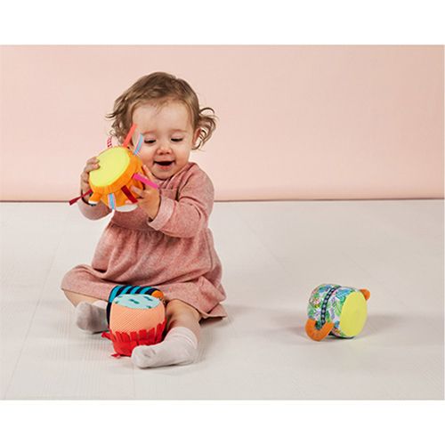 Een baby speelt lachend met een van de kleurrijke segmenten van de Lilliputiens activiteitenrammelaar.
