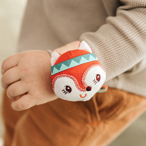 Een baby draagt de Lilliputiens rode vos armbandrammelaar om de pols.