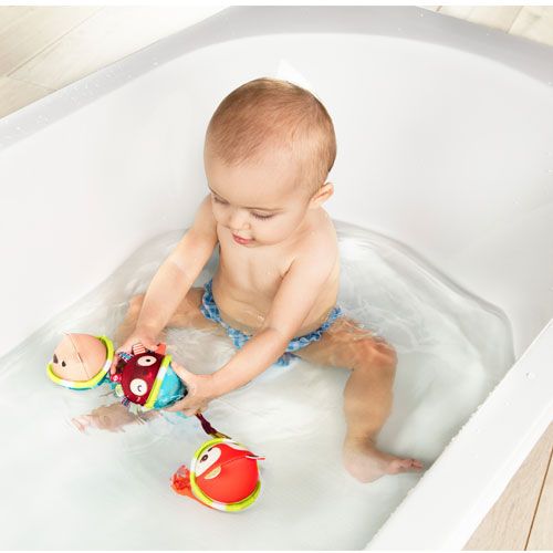 Een baby speelt in bad met twee Lilliputiens badballen met dierenfiguren.